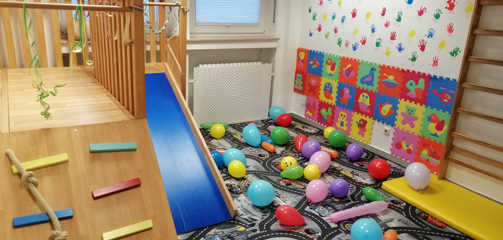 Innenraum mit buntem Spielteppich und Kletterelementen