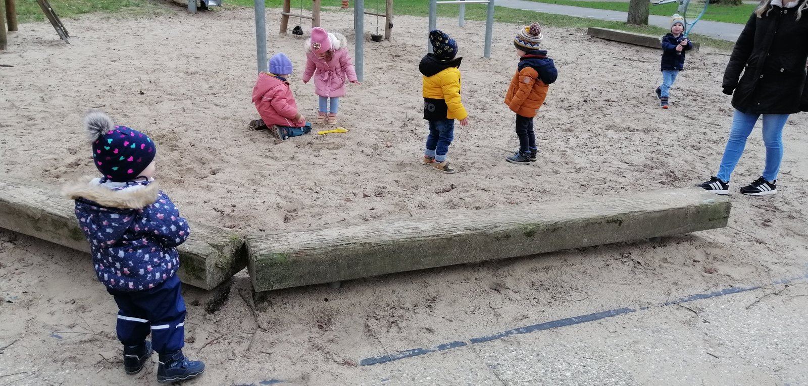 Kinder beim Spielen an einem Baumstamm