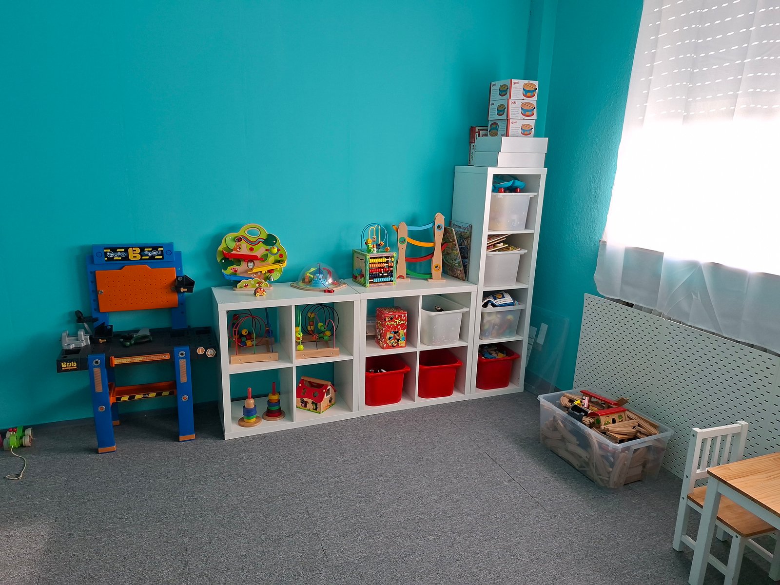 Türkisfarbener Spielraum mit Regalen und Kinderspielzeug